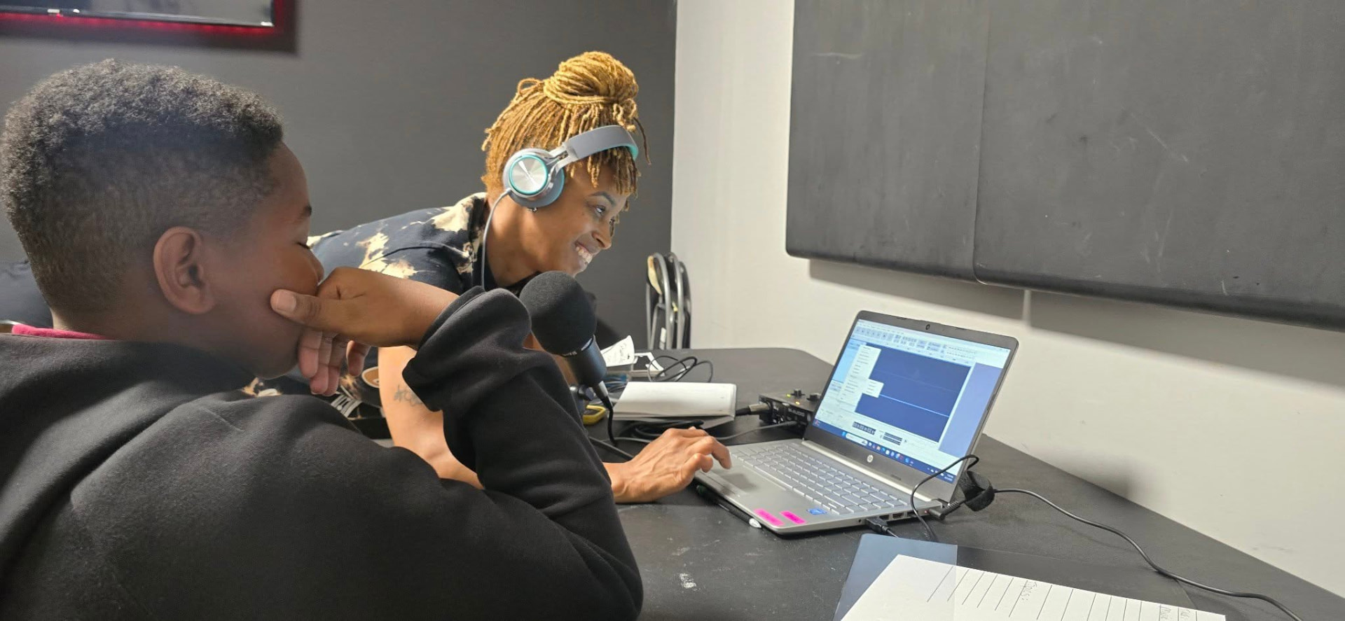 Youth recording audio with headphones at a laptop
